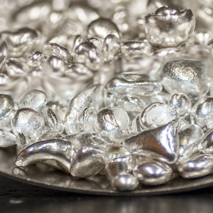 Sterling silver casting grain from Betts metals, refined from medical x-rays, sits on a silver plate. A close up crop of the casting grain.